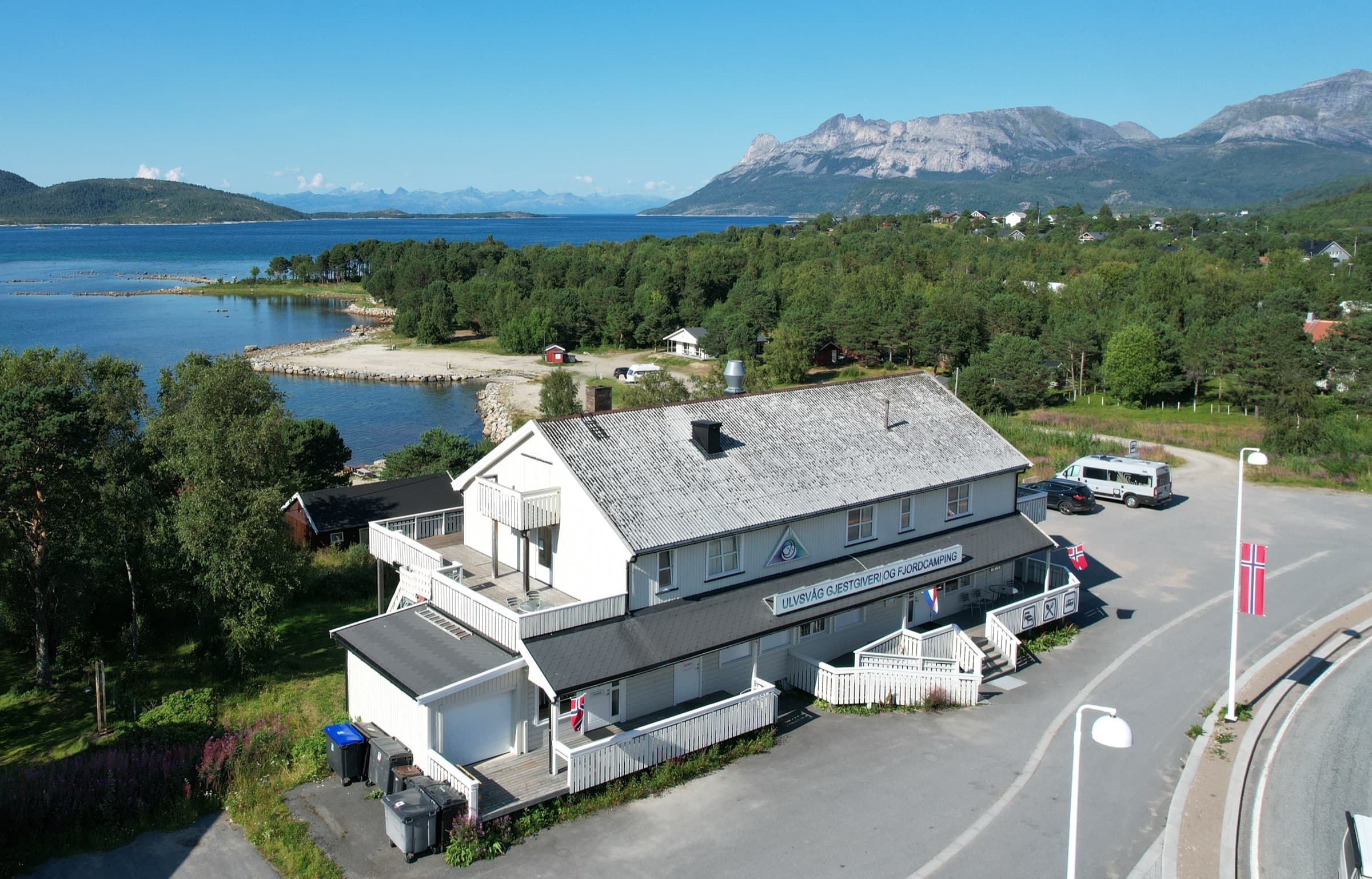 Gjestgiveriet og fjorden sett ovenfra, fjellene i Hamarøy bak.