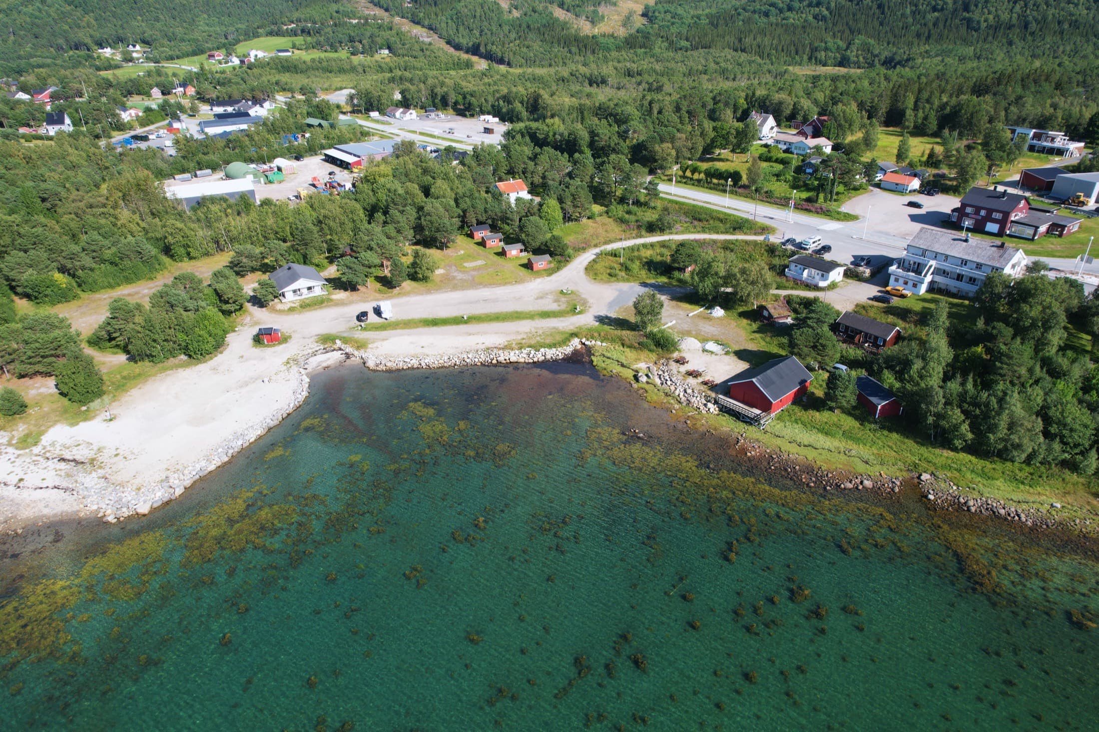 Ulvsvåg Gjestgiveri og Fjordcamping ovenfra, strandlinja og Vestfjorden.